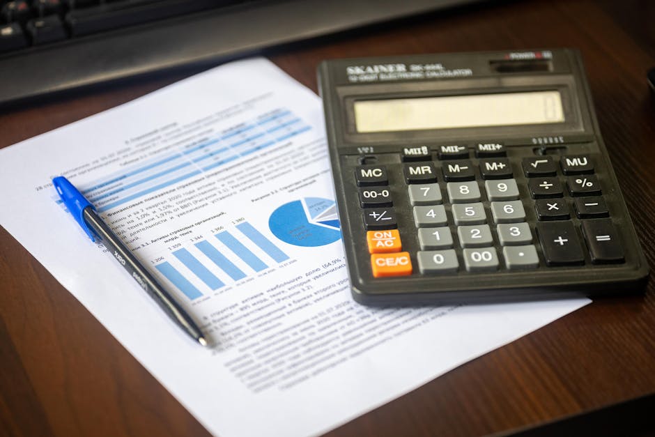 Close-up of a calculator, pen, and financial report on a wooden desk.